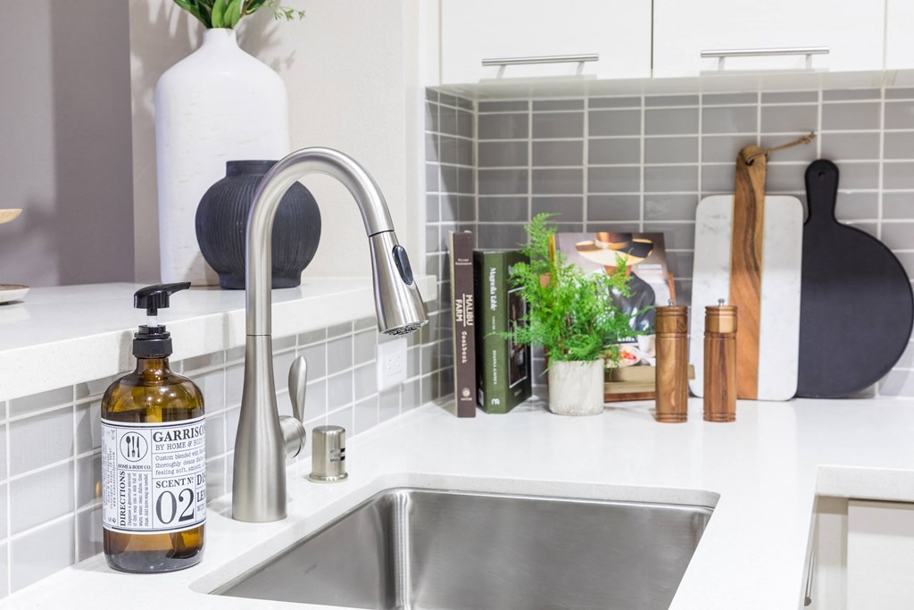 a white kitchen counter with a sink and a bottle of oil on it