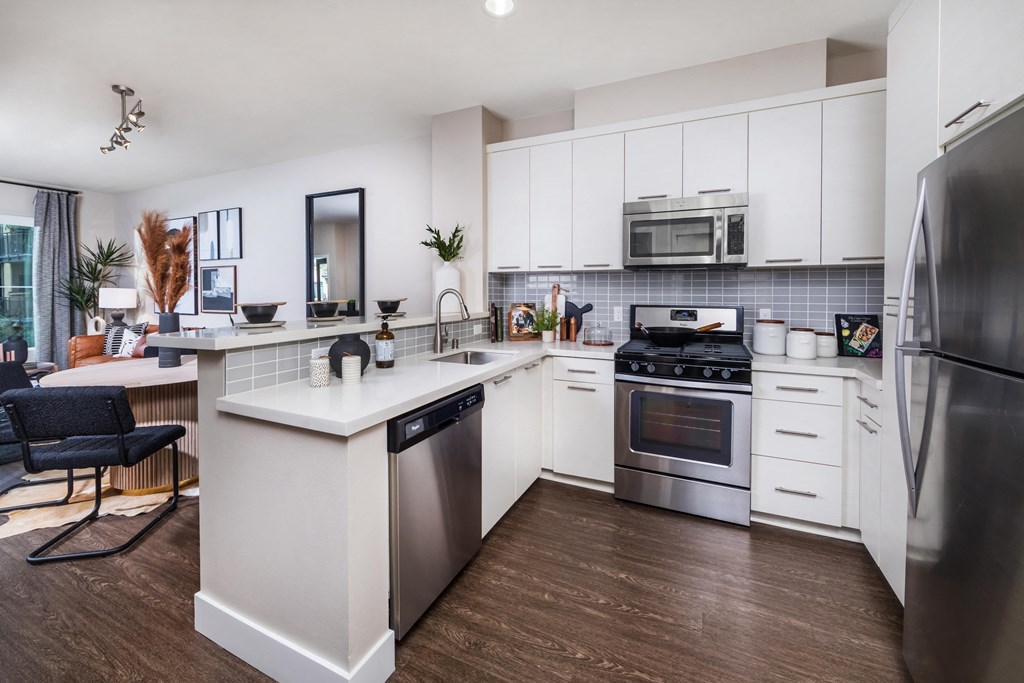 an open kitchen with stainless steel appliances and white cabinets