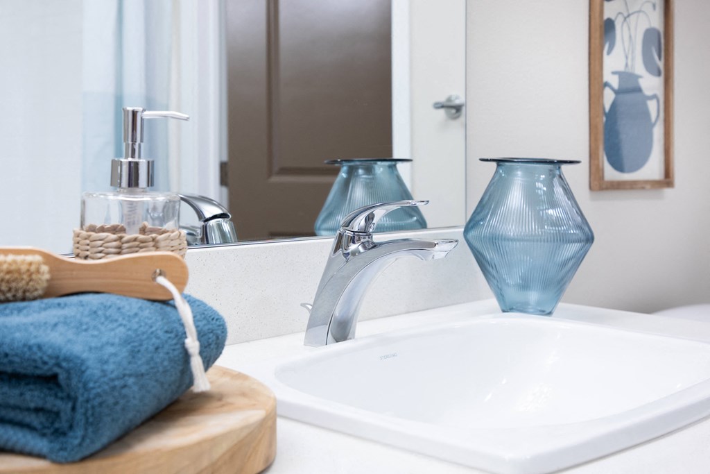 a bathroom sink with a mirror and a blue towel on a wooden cutting board