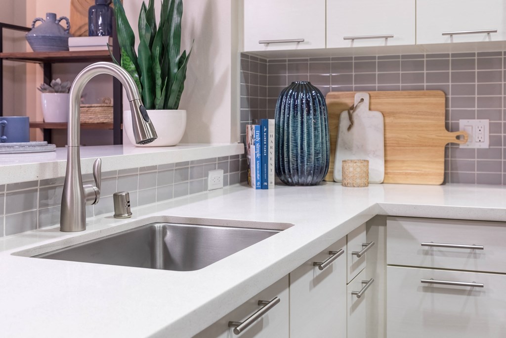 a white kitchen with a stainless steel sink and counter top