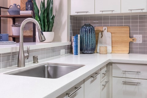 a white kitchen with a stainless steel sink and counter top