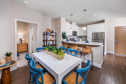 an open kitchen and dining area with a white table and blue chairs