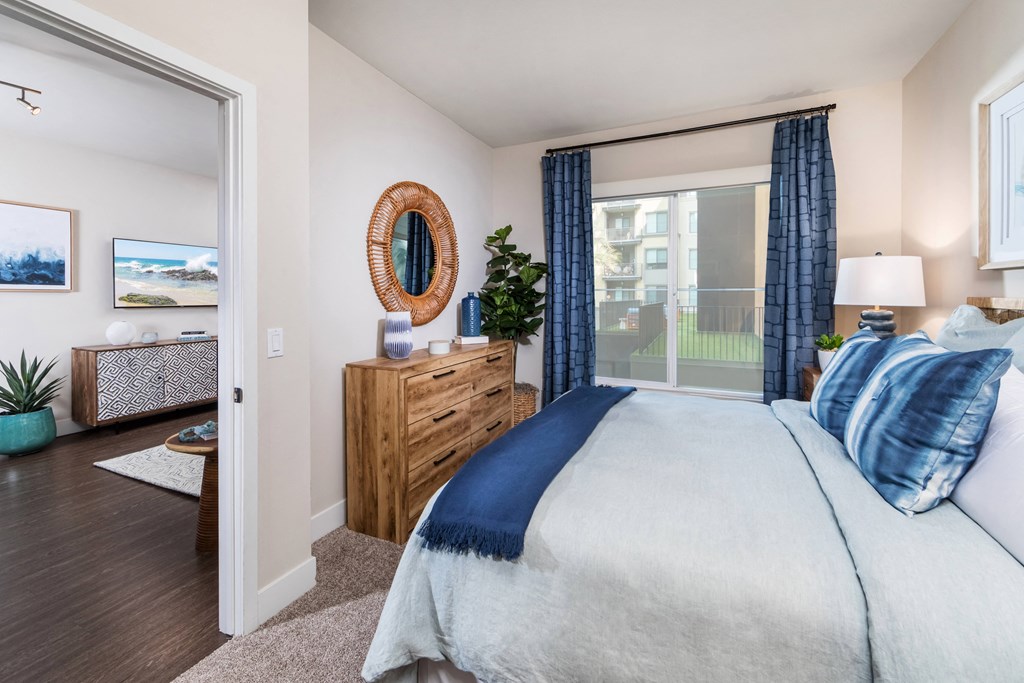 a bedroom with a large window and a bed with blue and white sheets