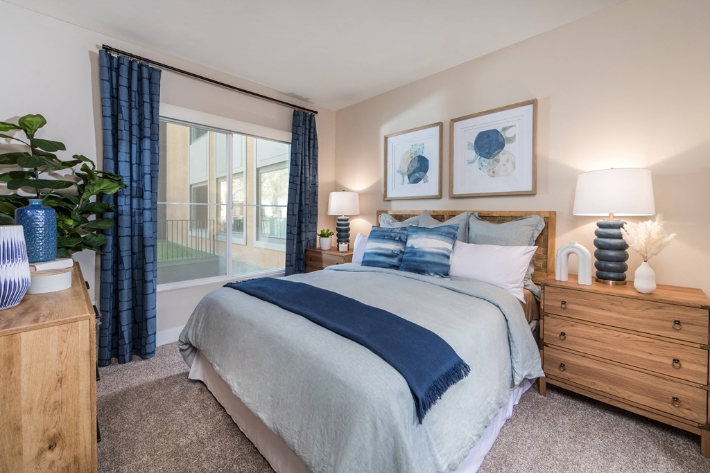 a bedroom with a large window and a bed with blue and white bedding