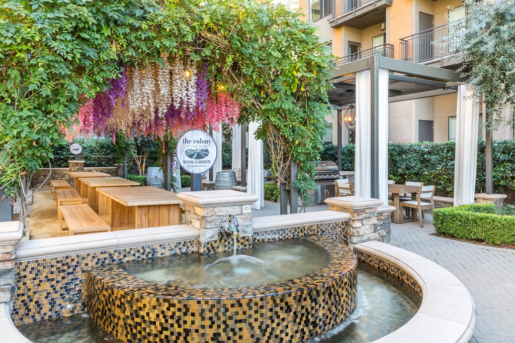 a fountain in front of a building with a tree and benches