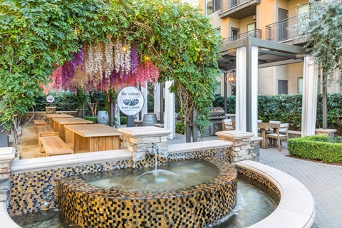 a fountain in front of a building with a tree and benches