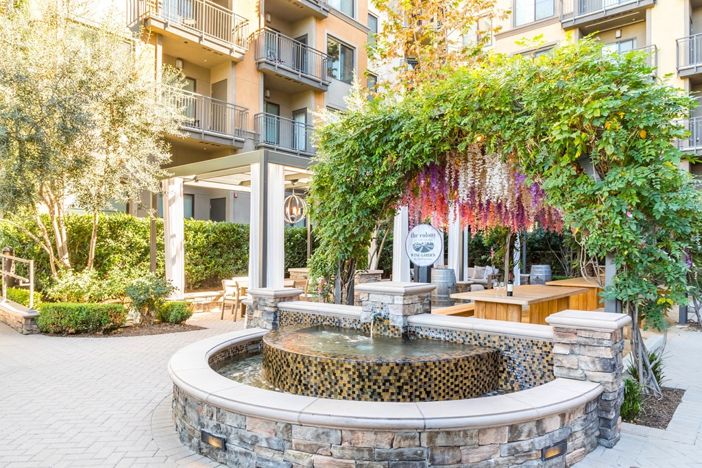 a fountain in a courtyard with a tree and an apartment building