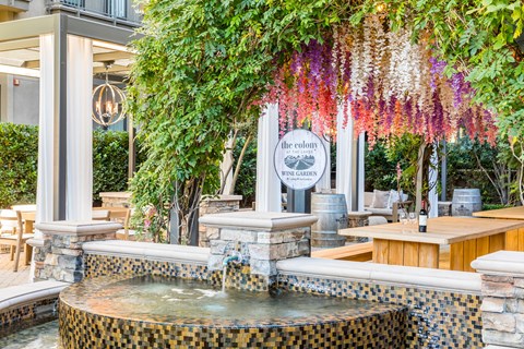 a fountain in front of a restaurant with flowers hanging over it