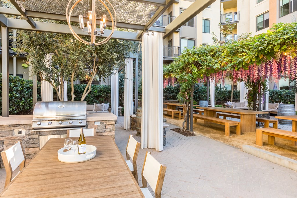 a patio with a dining table and a barbecue grill
