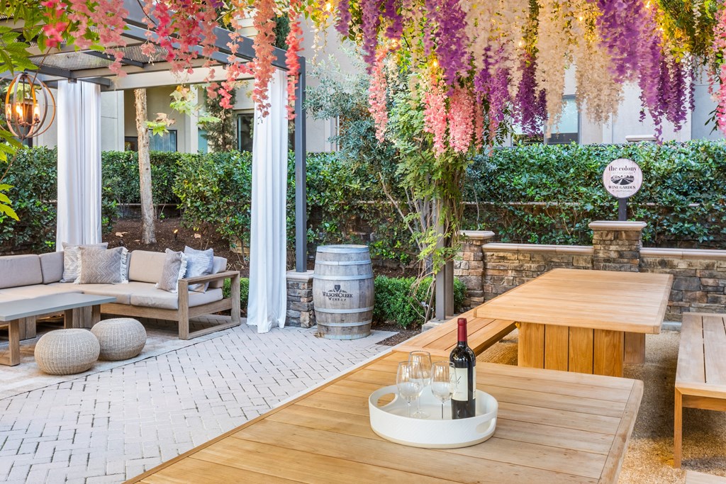 a patio with a table with a bottle of wine and a picnic table and chairs