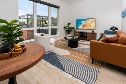 A living room with a brown couch, a wooden table, and a painting on the wall.
