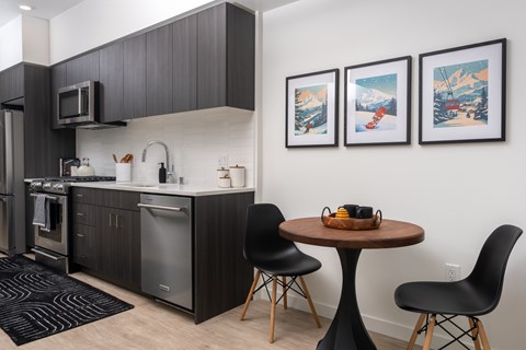 A kitchen with a table and chairs and three pictures on the wall.