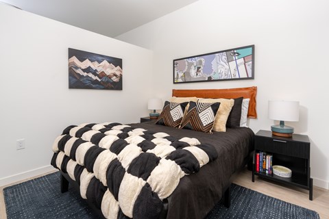 A bedroom with a large bed and two paintings on the wall.