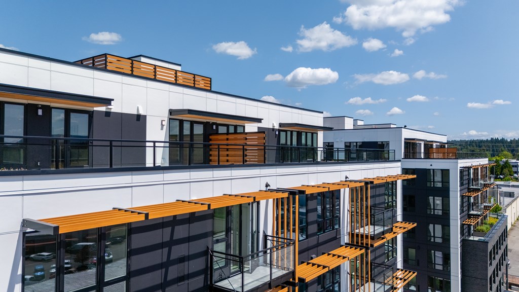 A modern building with a combination of white and black panels and orange wooden beams.
