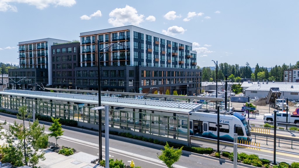 A modern train station with a train on the tracks and a building in the background.