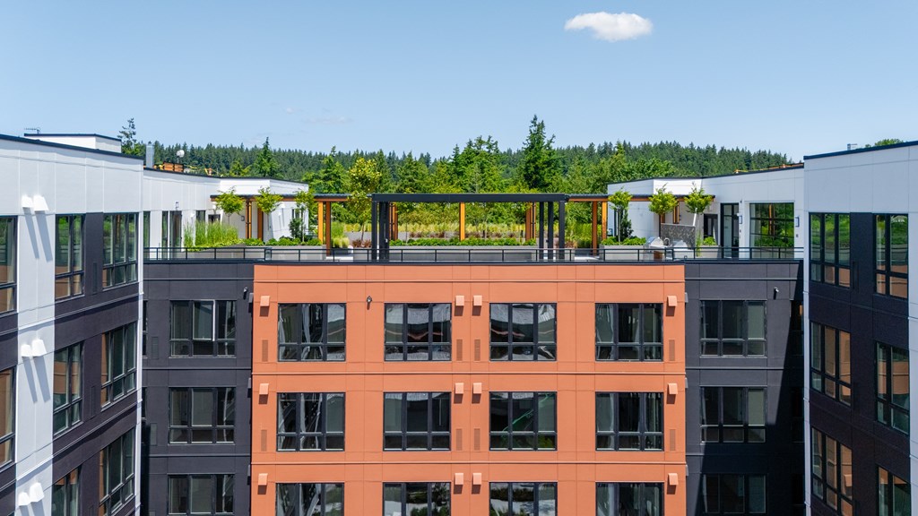 A modern building with orange and grey facades stands in front of a green landscape.