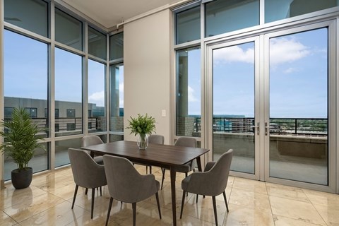 A dining room with a table and chairs in front of large windows.