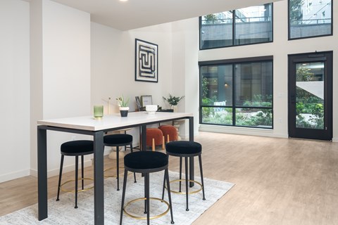A modern dining room with a white table and black stools.