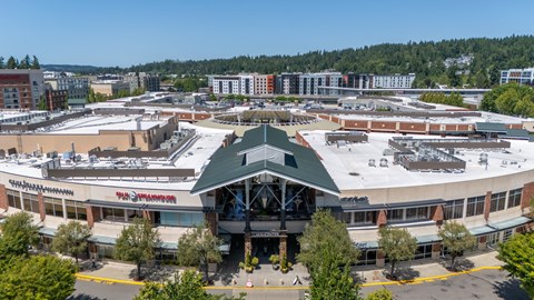 A large building with a green roof is surrounded by other buildings.
