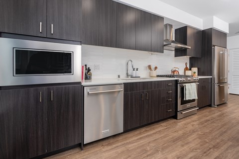 A modern kitchen with dark wood cabinets and stainless steel appliances.