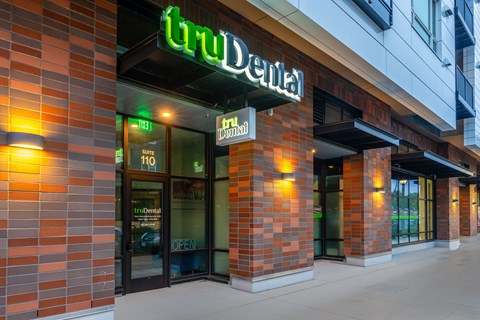 A brick building with a green sign that says "In-Dental" on it.