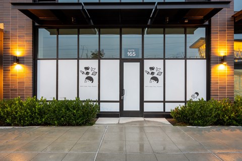 The image shows a building entrance with a glass door and a sign that reads "165".