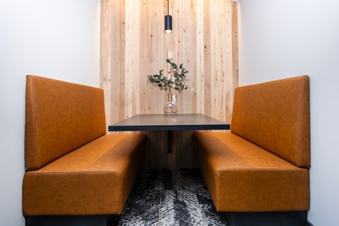 two orange chairs and a table in front of a wooden wall