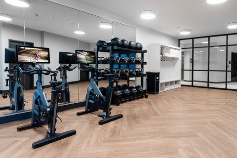 a gym with exercise machines and weights on a wooden floor