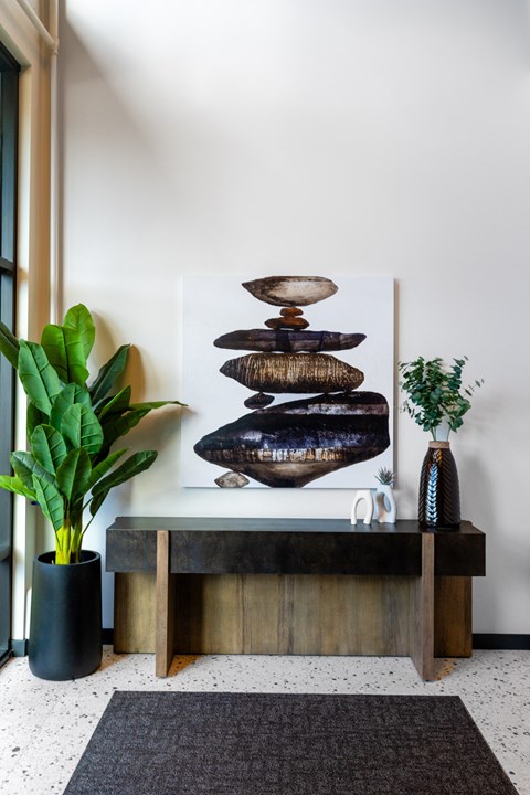 a reception area with a wooden table and a wall mounted sculpture of rocks