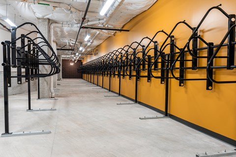 a row of bike racks in a building with a yellow wall