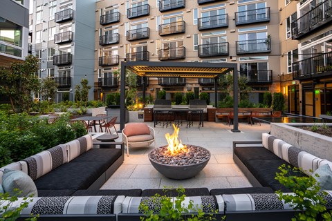 an outdoor patio with a fire pit in front of an apartment building