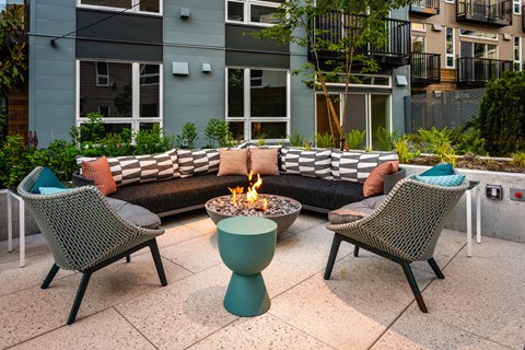 a fire pit on a patio with chairs and a couch