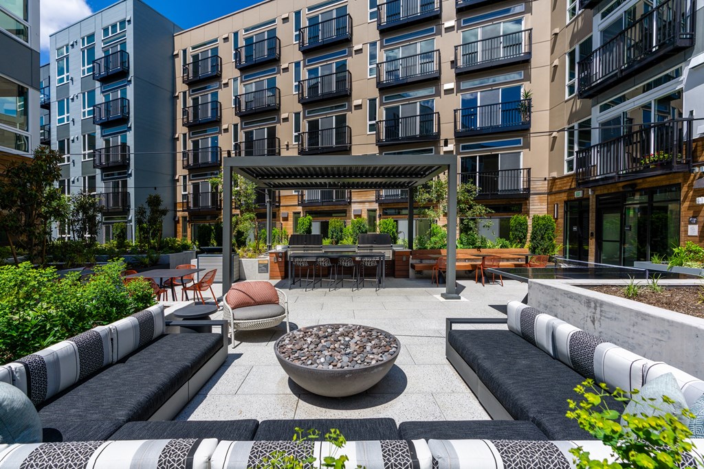 an outdoor patio with couches and a fire pit in front of an apartment building