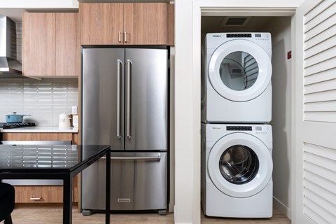 a washer and dryer in a kitchen next to a stainless steel refrigerator