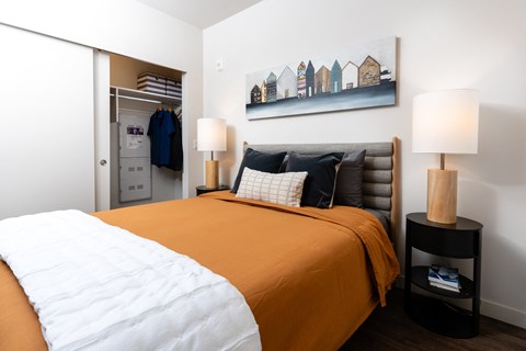 a bedroom with an orange bed and a painting on the wall