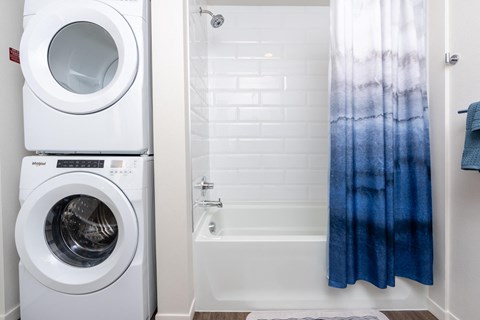 a bathroom with a washing machine and a tub and a shower with a shower curtain