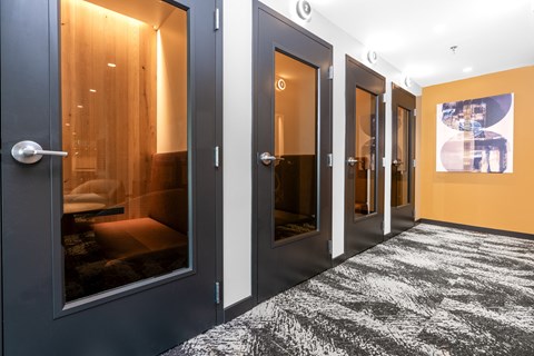 a row of black doors in a hallway with orange walls and a rug