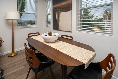 A dining table with a bowl of fruit on it and chairs around it.