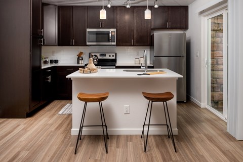 A kitchen with a white countertop and brown stools.