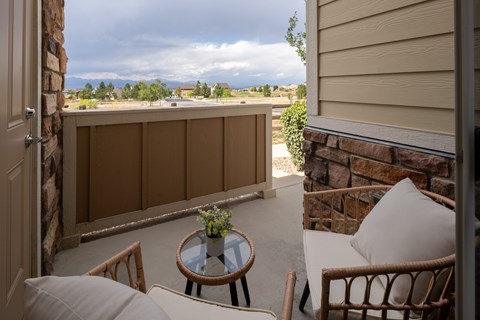 A balcony with a table and chairs overlooking a cloudy sky.