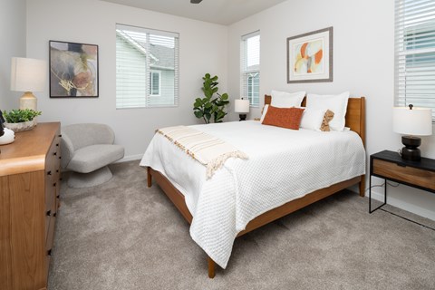 A bedroom with a bed, nightstand, and chair.