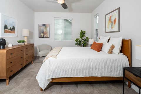 A bedroom with a bed, nightstand, and a plant.