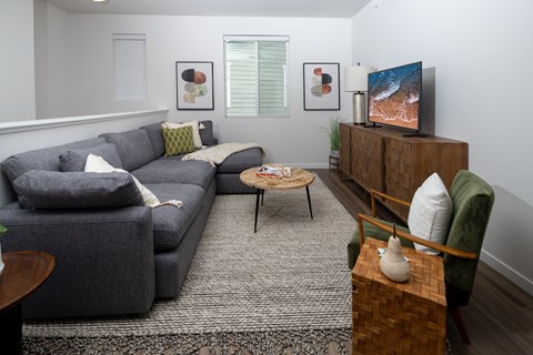 A living room with a grey couch, a wooden coffee table, and a television on a wooden cabinet.