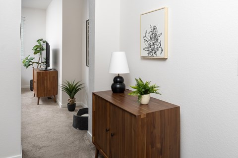 A room with a wooden cabinet, a lamp, and a potted plant.