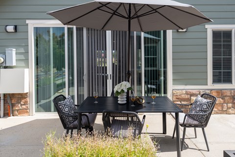 A patio with a table, chairs, and an umbrella.