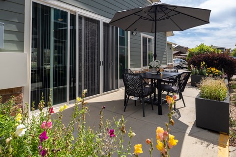 A patio with a table and chairs and flowers.