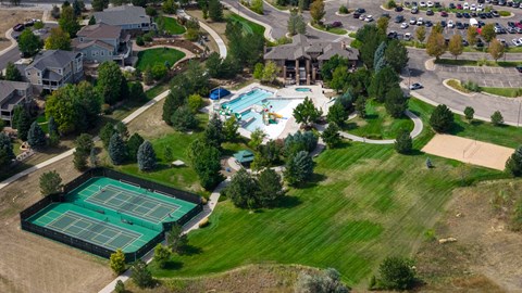 An aerial view of a tennis court surrounded by a grassy area and a pool.
