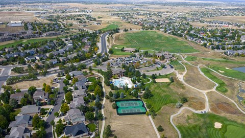 A golf course is surrounded by houses and a large open field.
