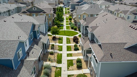 A row of houses with a green lawn in between.