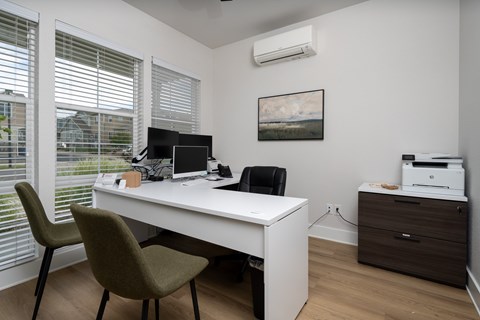 A white desk with a laptop and a printer on a wooden floor.